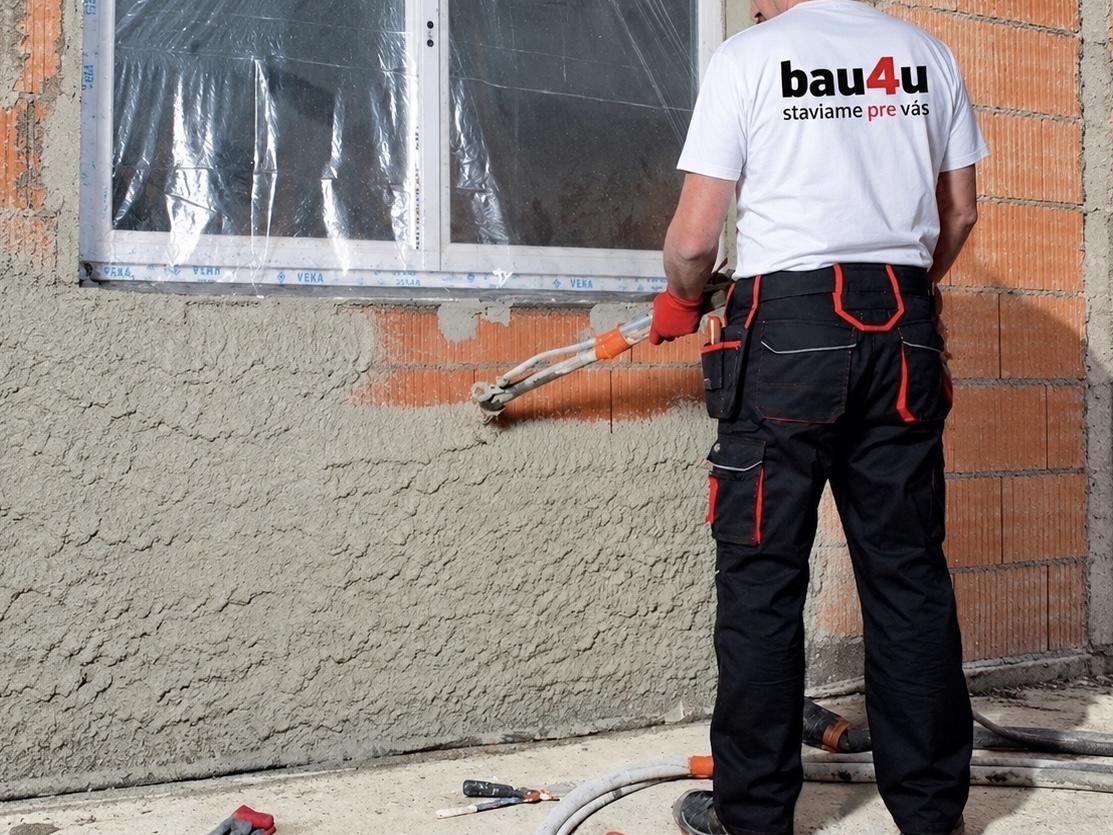 Pracovník BAU4U nanáša strojovú omietku na tehlovú stenu
